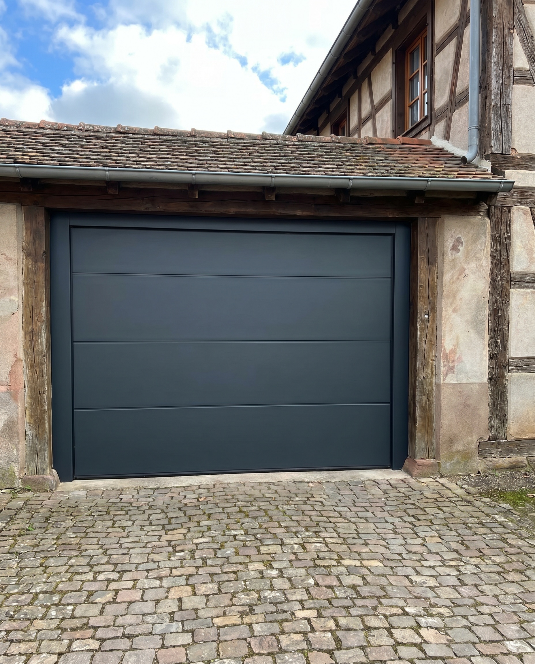 Porte de garage sectionnelle aluminium gris anthracite installée sur une maison à Mulhouse